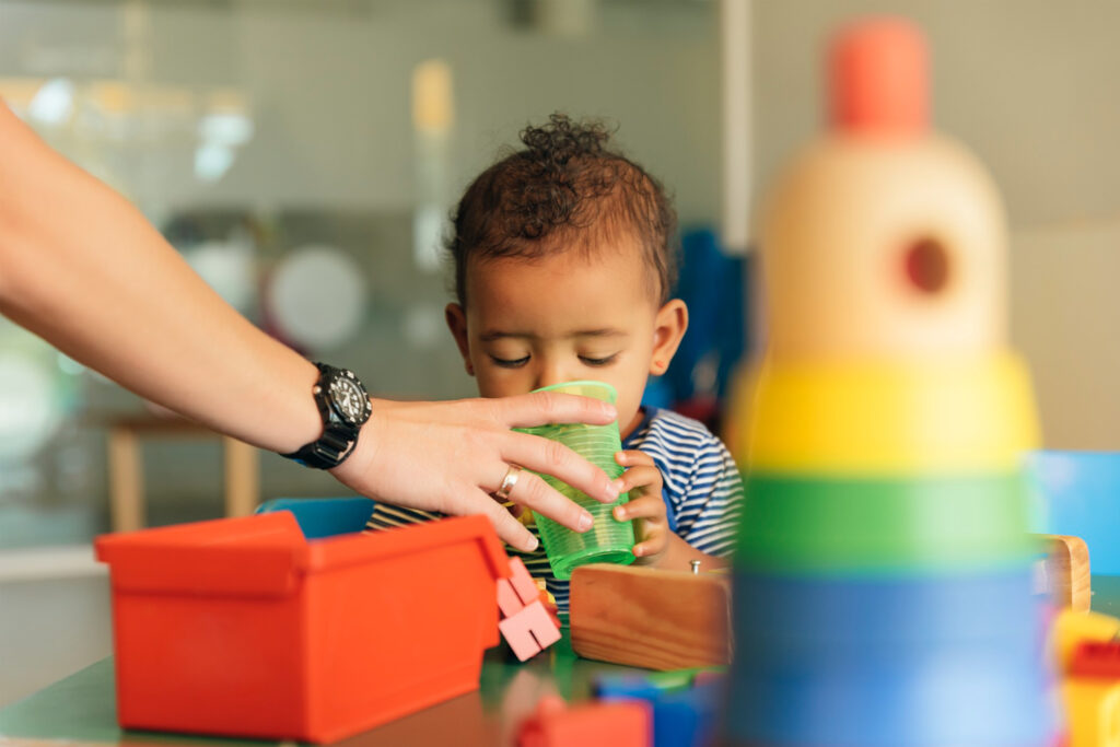 Toddler with blocks being given juice